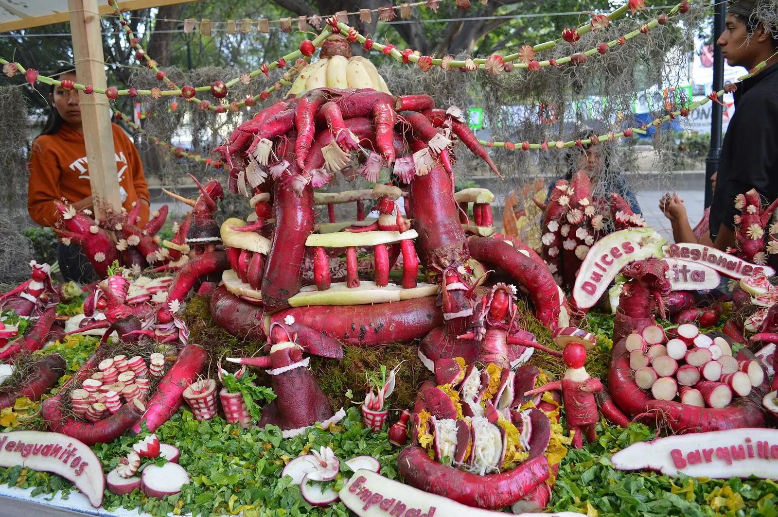 Figuras talladas en rábano en la Noche de Rábanos de Oaxaca, con letreros y adornos de rábano