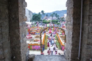 Altares y arcos de flores de cempasúchil en la plaza de Huejutla, Hidalgo, durante el Xantolo, vistos desde una ventana de piedra
